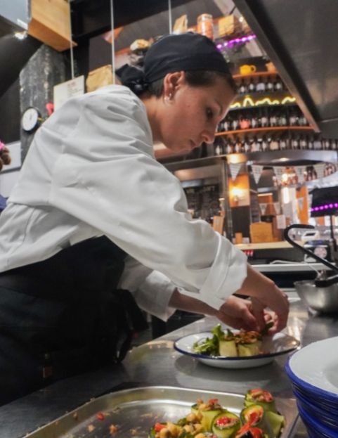 Un pâtissier découpe l'excédent de pâte autour d'un moule à tarte pour préparer une tarte au chocolat.