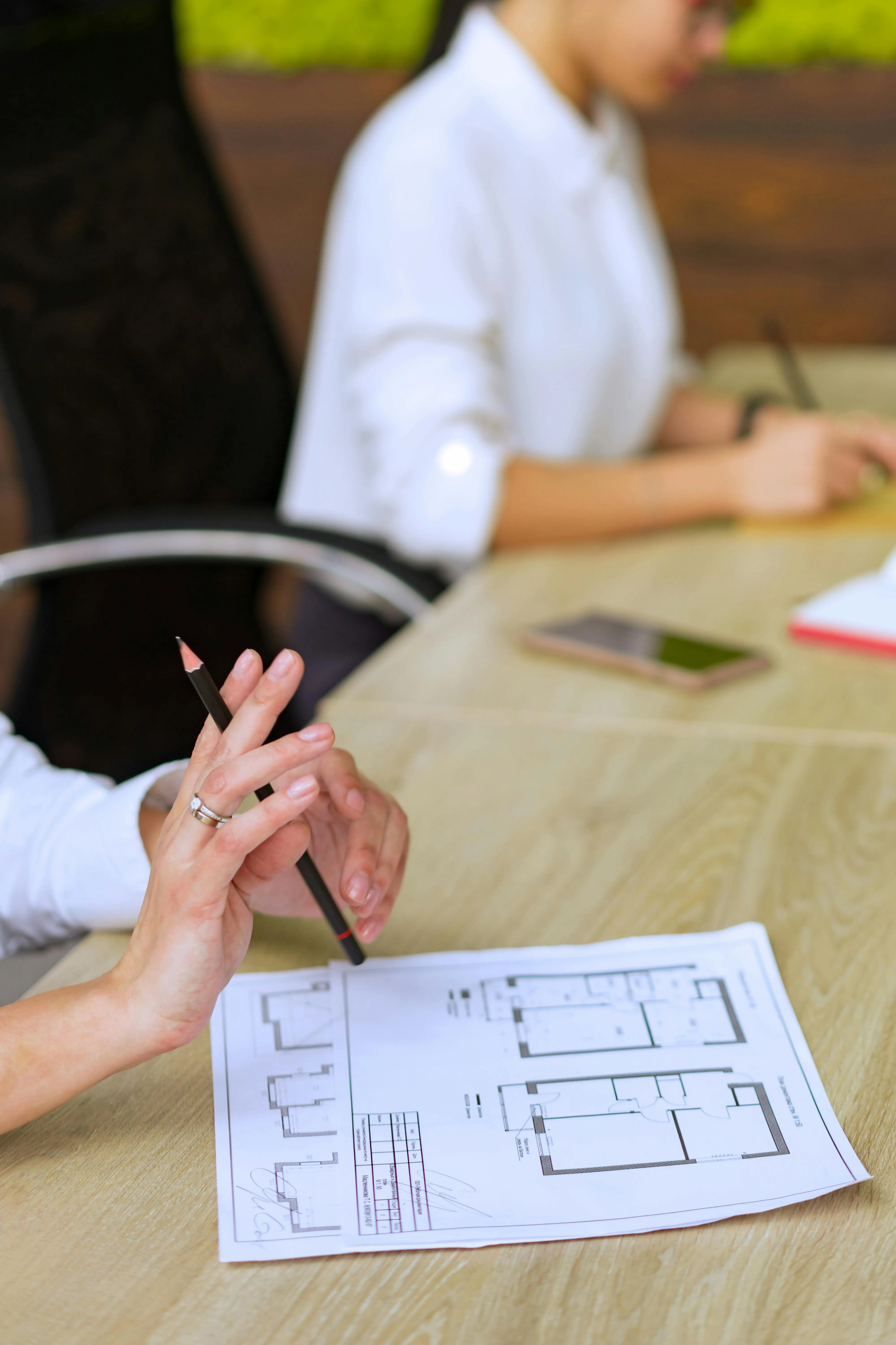 Conseiller annotant un plan d'appartement avec un acquéreur