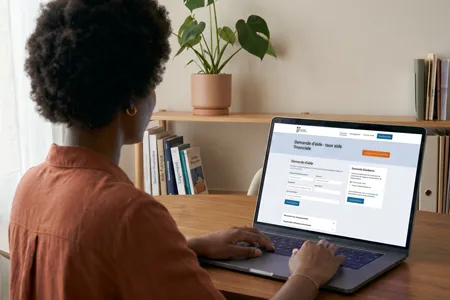 Personne utilisant un ordinateur portable pour remplir une demande d'aide financière en ligne.