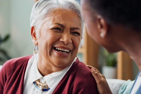 Femme âgée souriante avec une main rassurante posée sur son épaule.