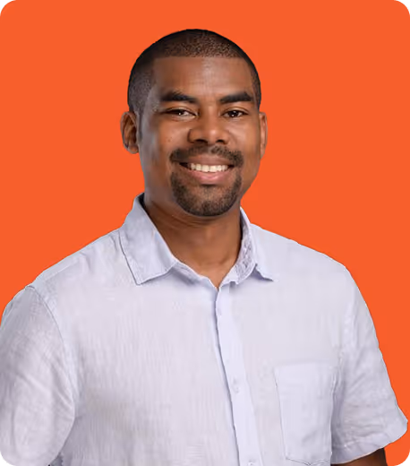 Homme souriant en chemise blanche devant un fond orange uni.