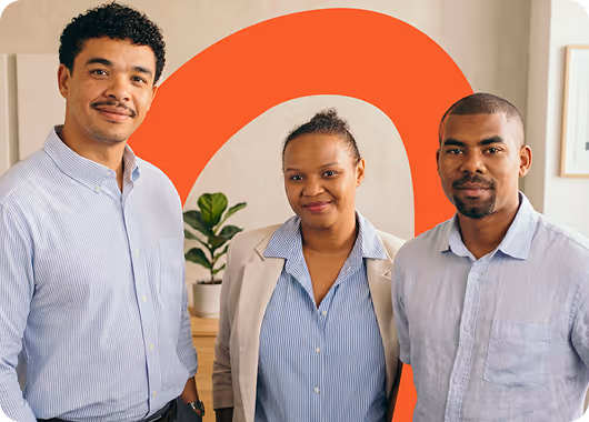 Trois personnes souriantes posent devant un mur avec un grand cercle orange.