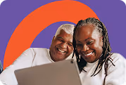 Deux femmes souriantes regardant un ordinateur portable devant un fond orange et violet.
