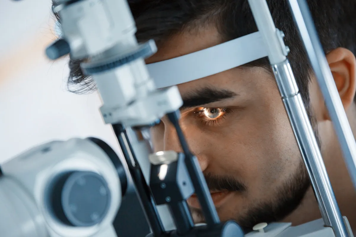 Man undergoing eye examination using a slit lamp in an optical clinic.