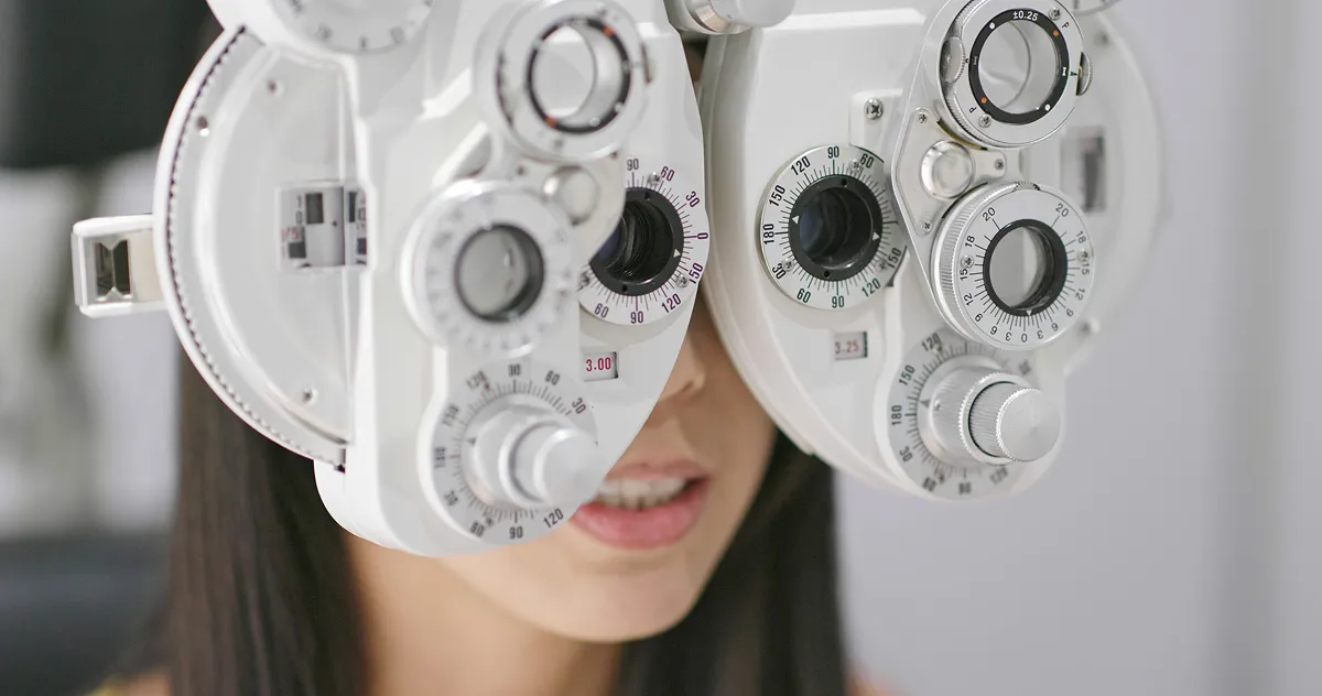 Close-up of a woman undergoing an eye test using a phoropter device.