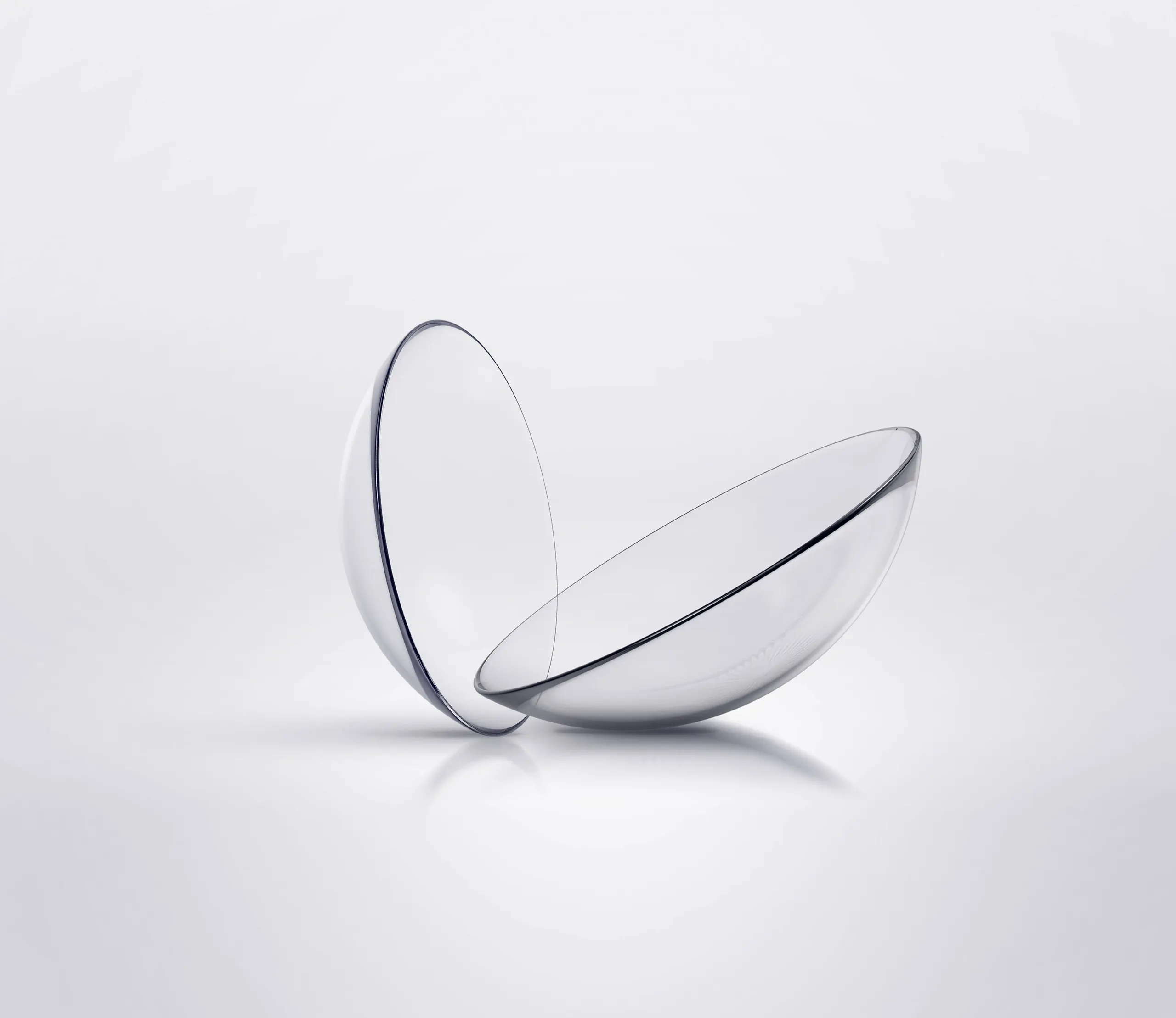 Two clear contact lenses on a pale grey background