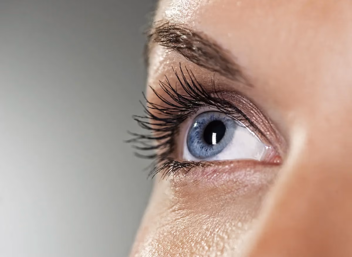 Close-up of a young woman's blue eye with long lashes — eye health and vision care