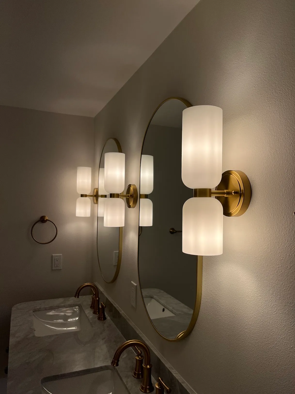 Bathroom vanity mirror framed by two newly installed sconce lamps