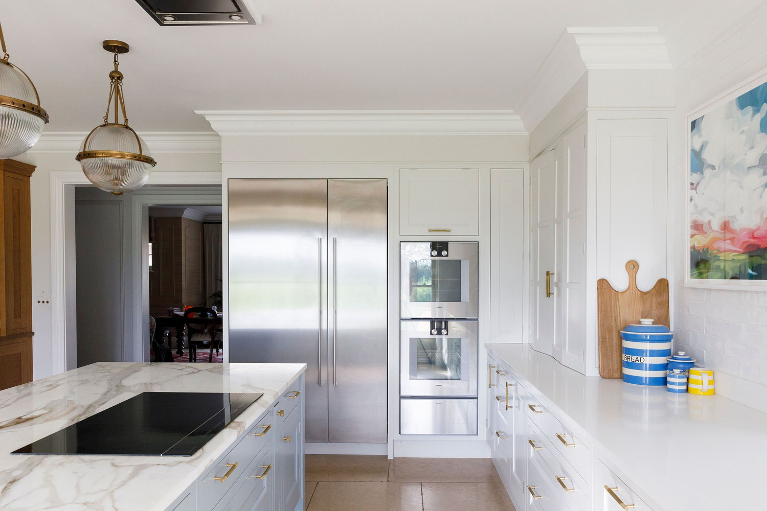 Open-plan coastal kitchen with neutral and soft-blue palette and cheerful accents — Lorna Smith Interiors, West Sussex