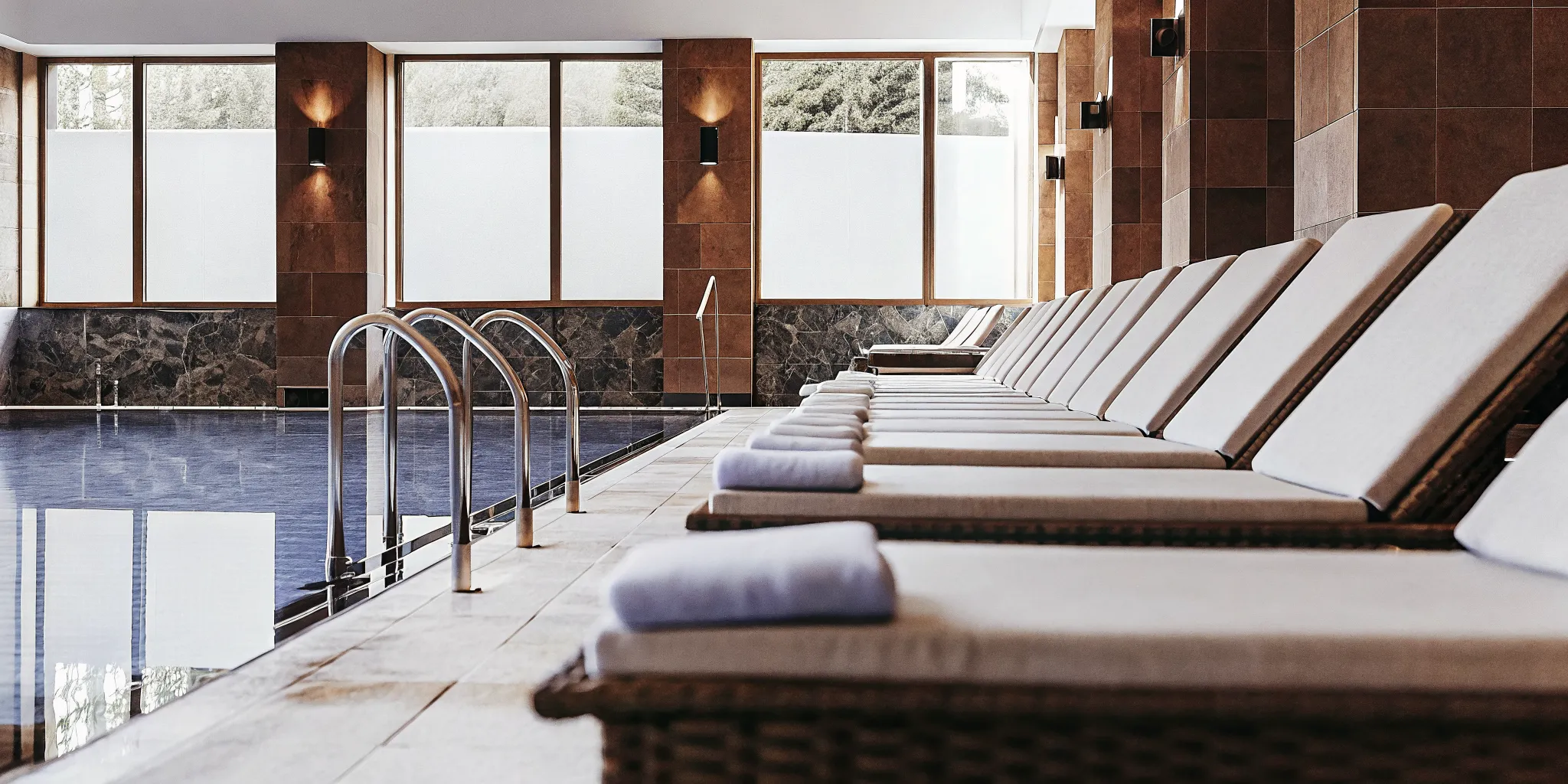 A luxurious indoor wellness pool with tranquil blue water and lounge chairs