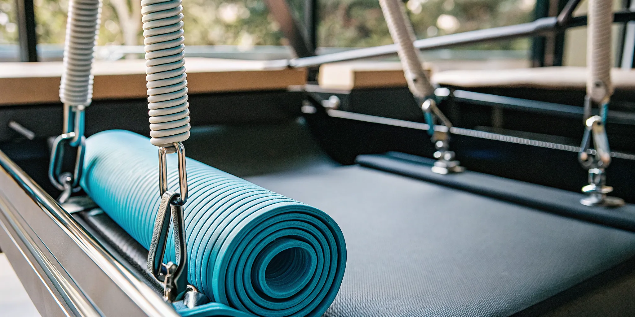 Reformer Pilates machine beside a mat for a reformer Pilates vs mat Pilates comparison