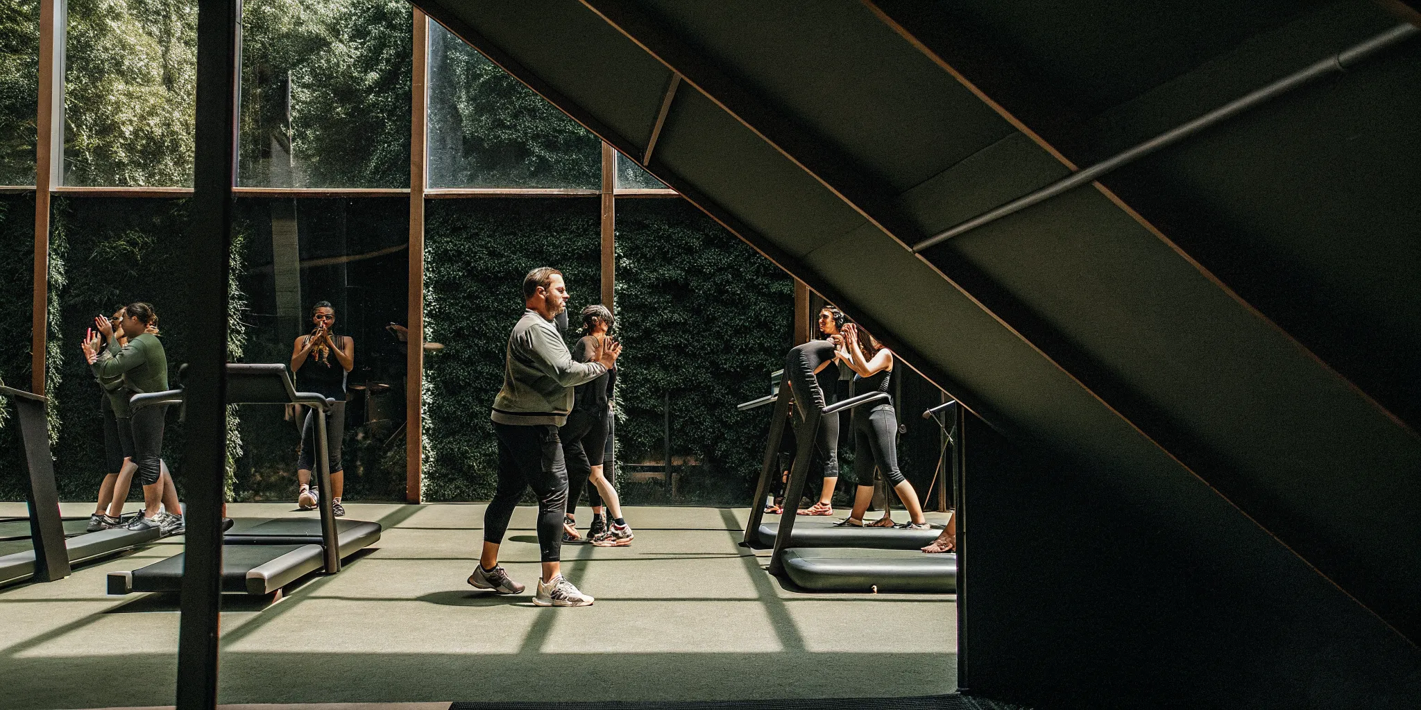 Personal trainer coaching a member while a group fitness class trains nearby