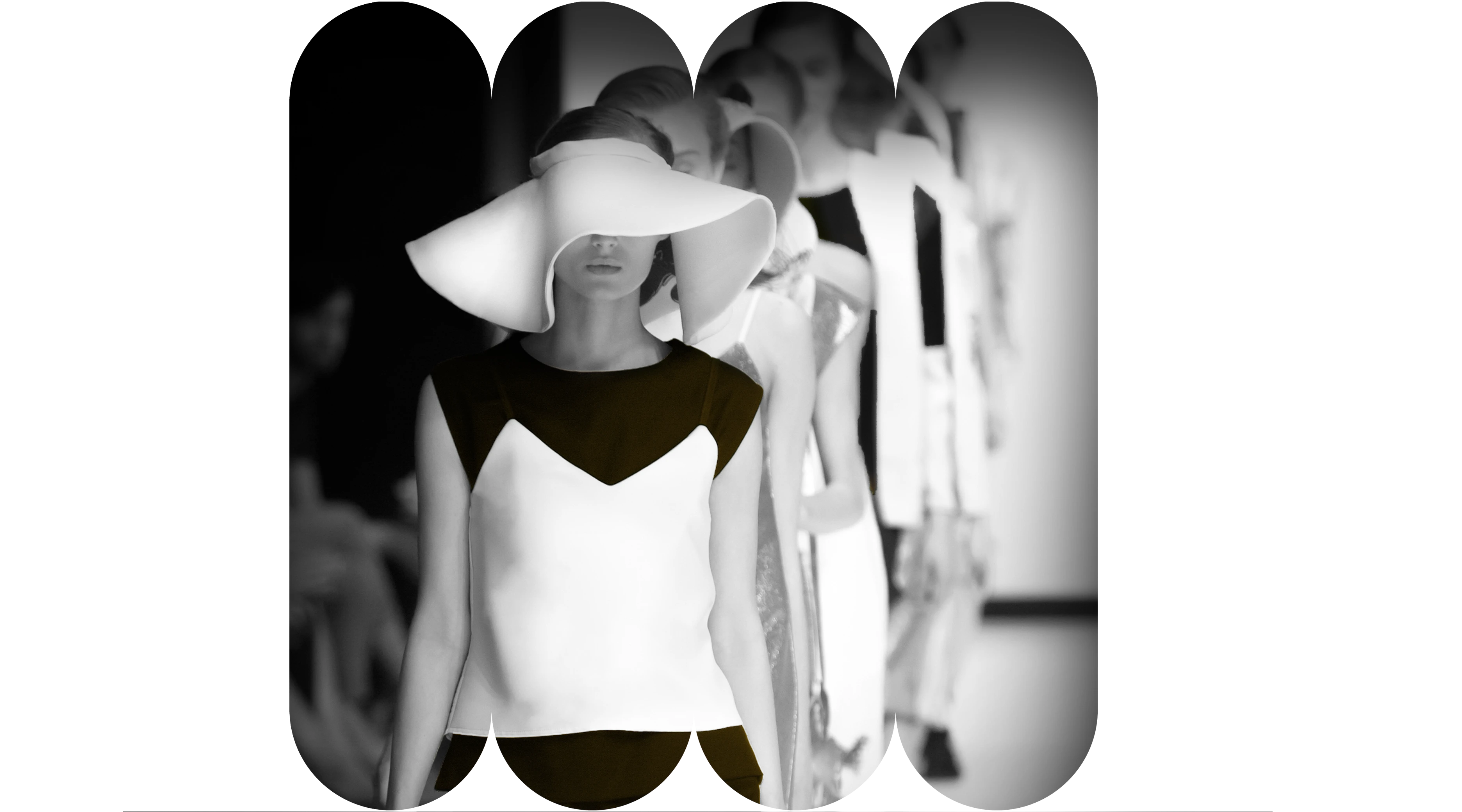 Models in black and white outfits with wide-brim hats walking in a fashion show lineup.
