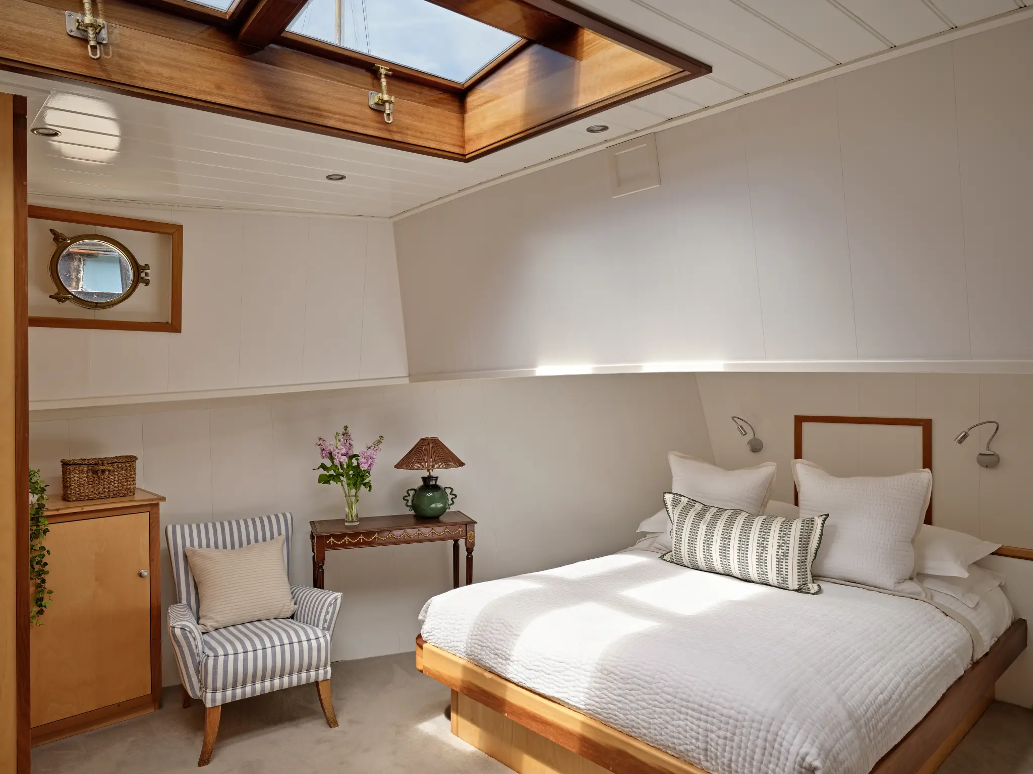 Interior of a modern narrowboat with a dining table set for four, a kitchen with dark cabinets, and a cozy seating area with colorful cushions.