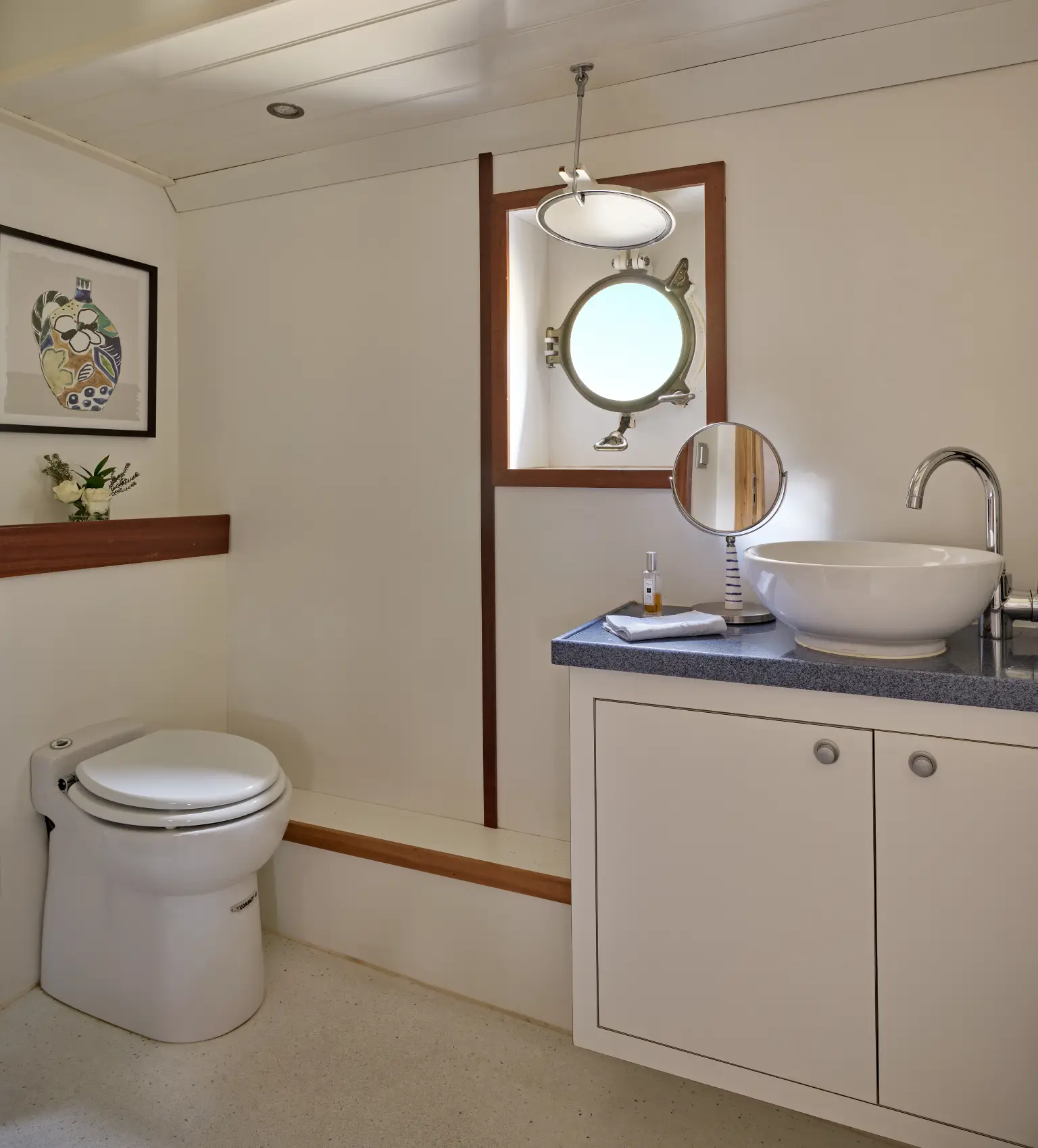 Modern bathroom vanity with navy blue cabinets, a white rectangular sink, round mirror, and wall-mounted black faucet.