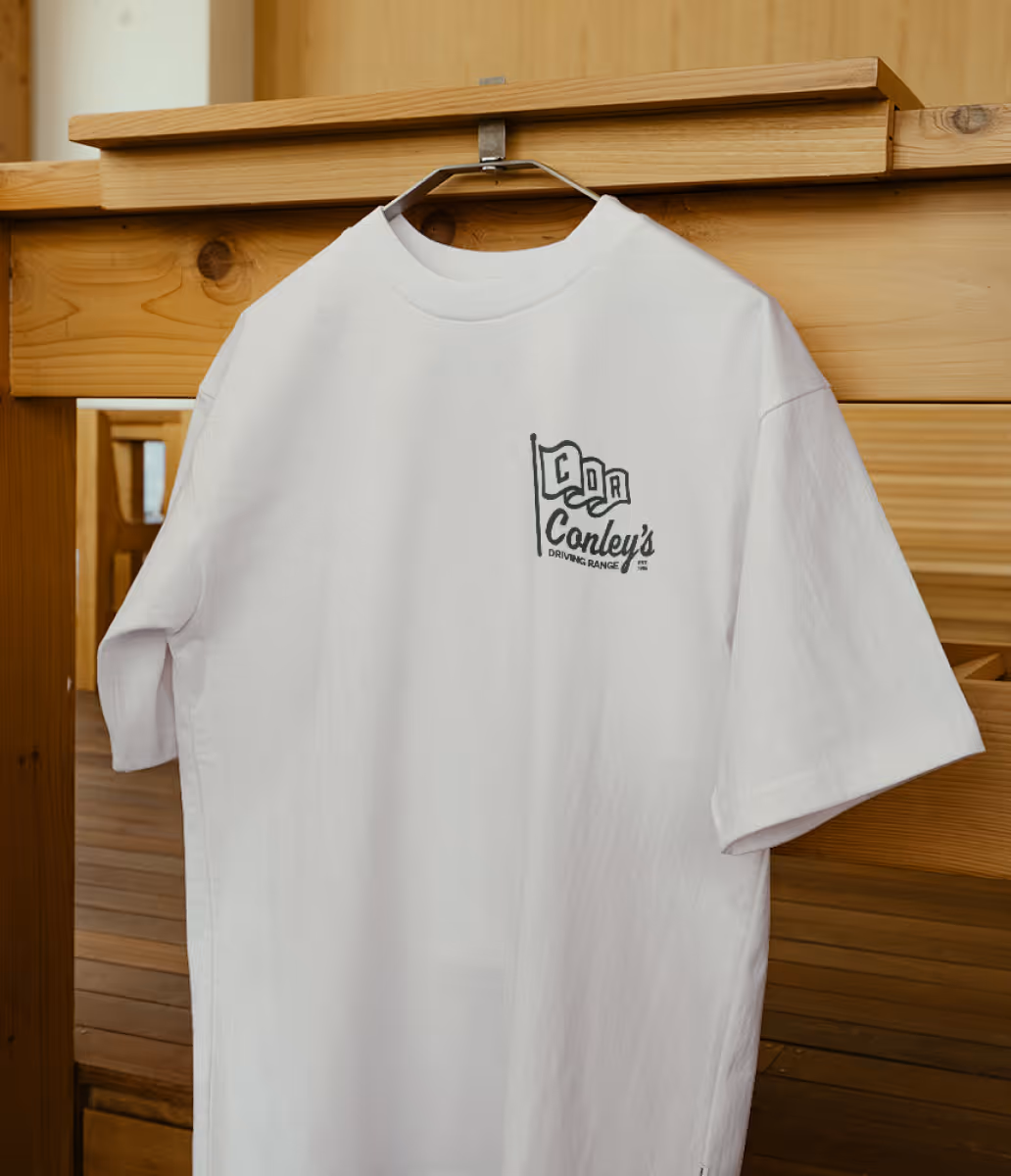 Conley's Driving Range logo on a white t-shirt hanging from a dresser.