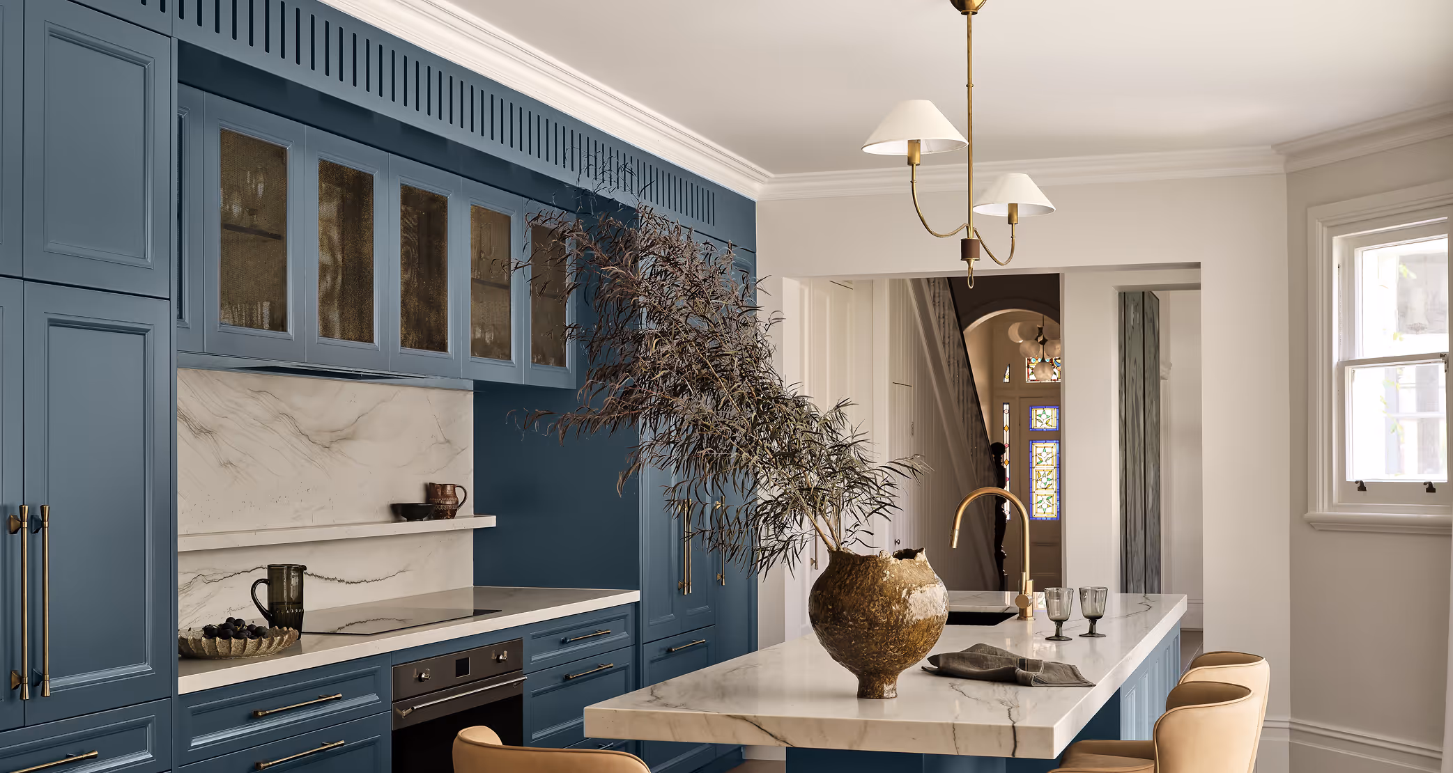 Interior of a kitchen with blue cupboards and white countertops.