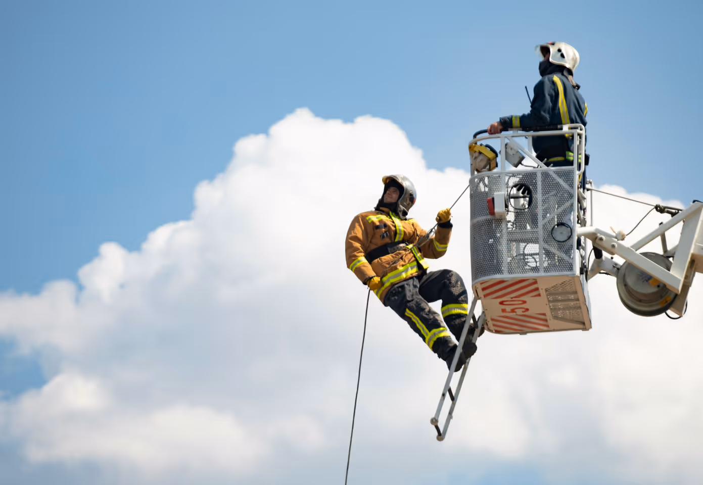 Firefighters in ladder bucket and propelling from bucket.