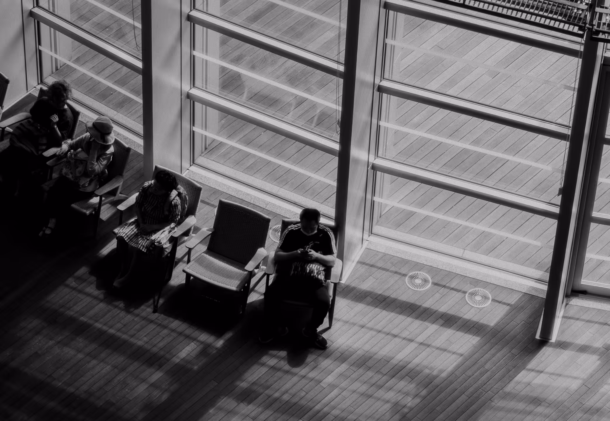 Four people sitting in chairs in front of a large window.