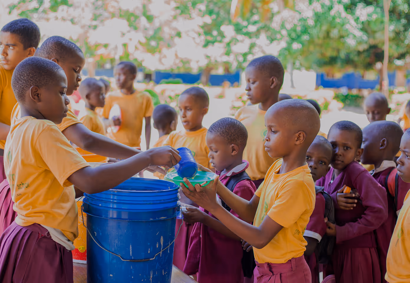 several children pass out water in an African village