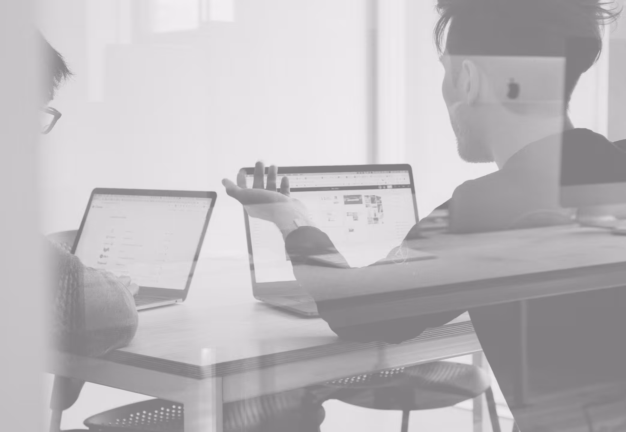 Two people sitting at desks with computers.