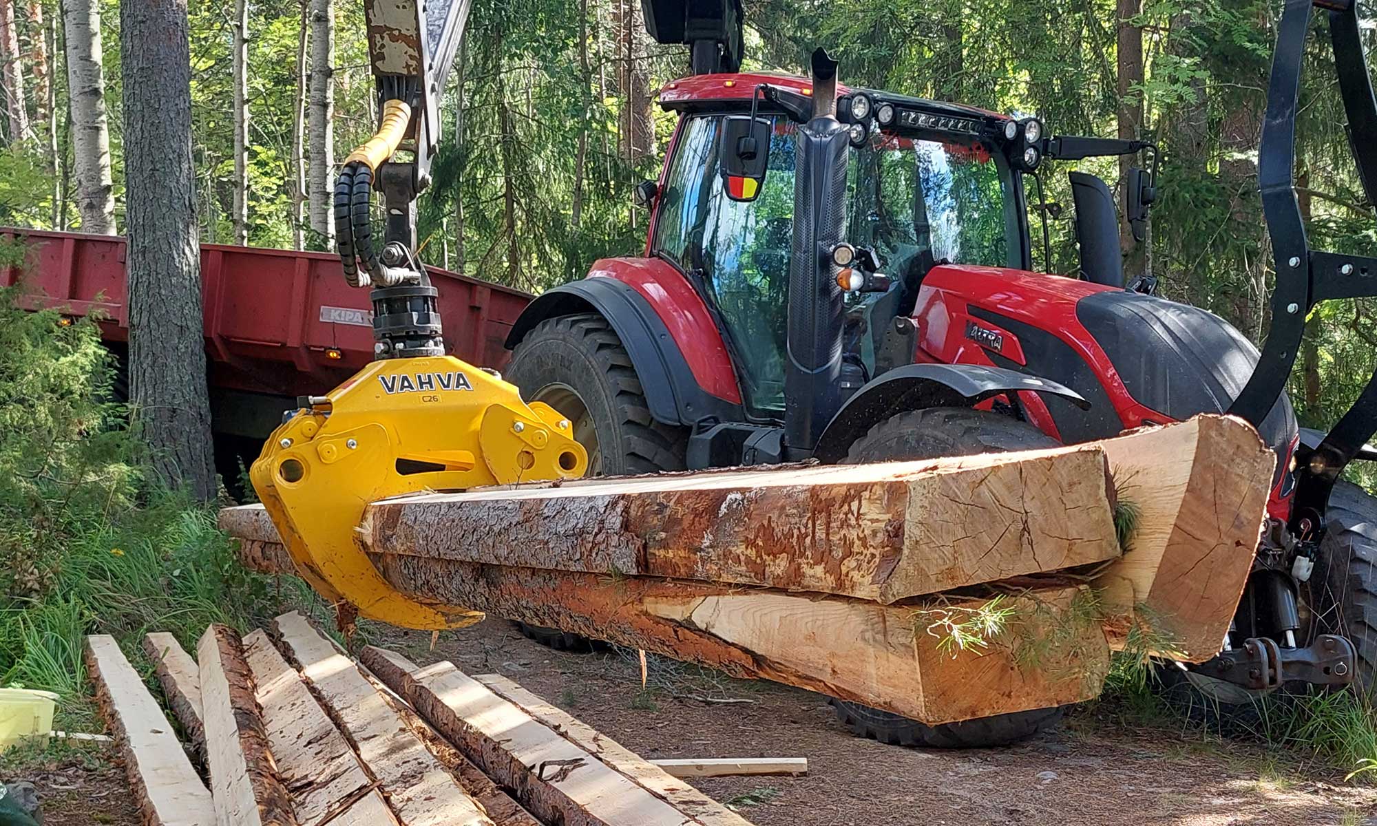 Traktori ja puutavarakoura puunrungon käsittelyssä metsässä