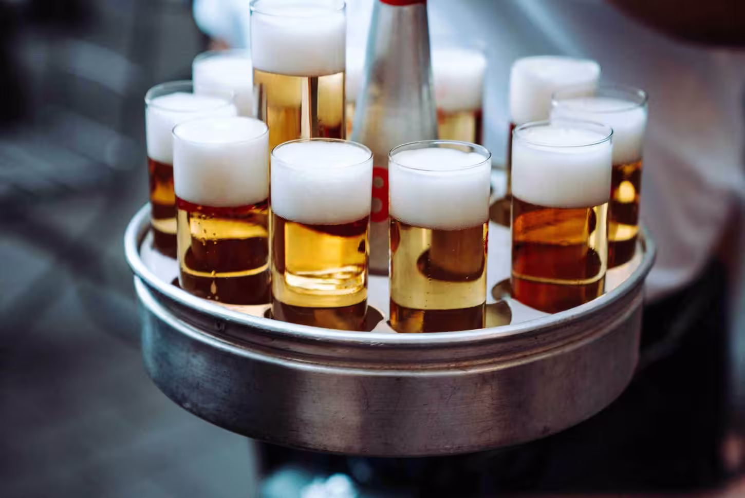 Köbes trägt rundes Tablett voll mit frisch gezapften Kölsch-Gläsern durchs Brauhaus