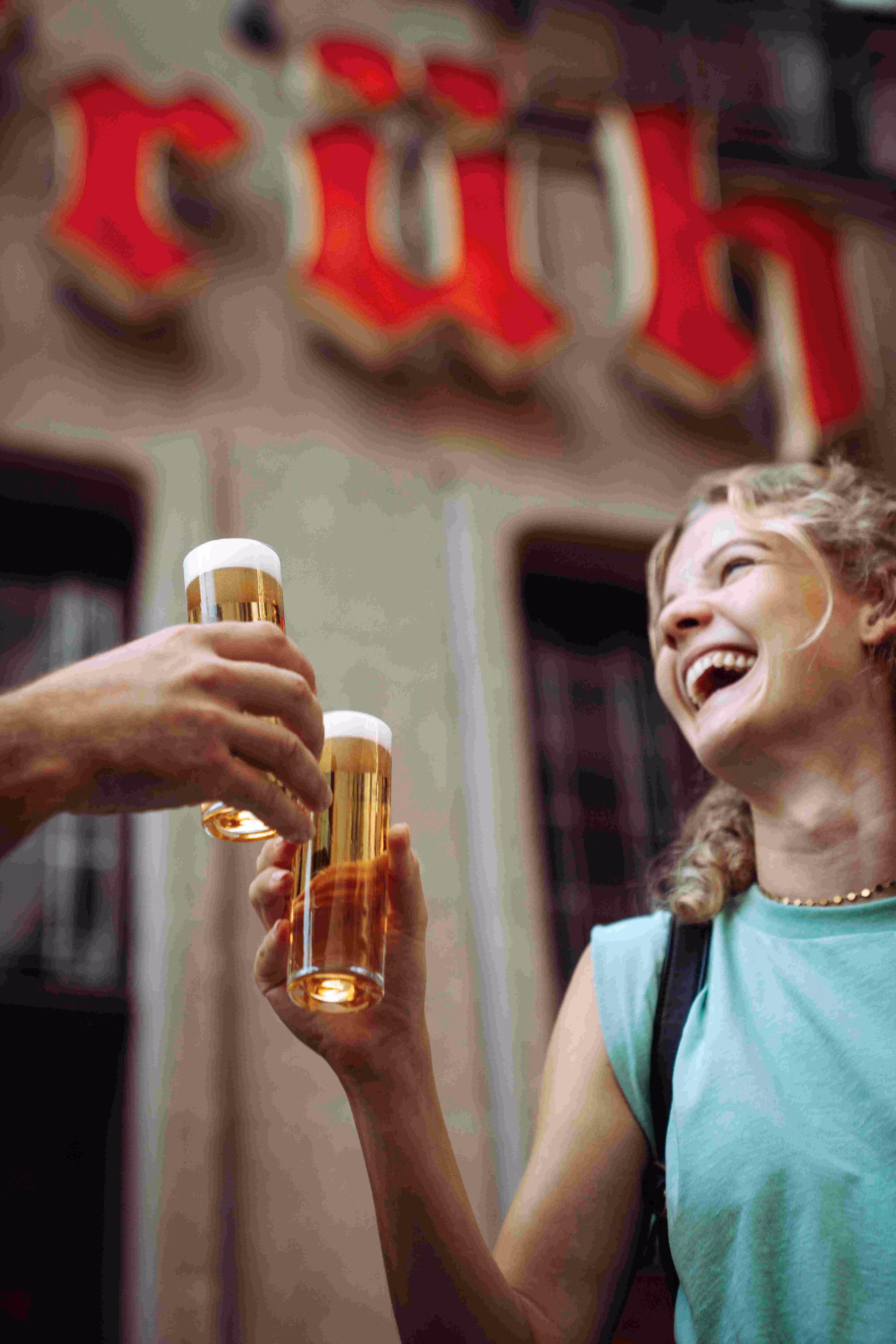 Nahaufnahme: lachende Frau stößt mit Kölsch-Glas vor Früh Brauhaus in Köln an