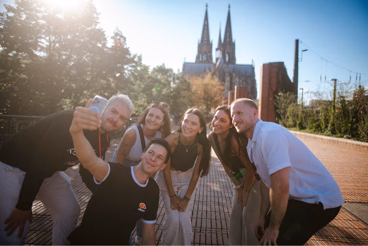 Kölner Kompass Tourguide macht mit Gästegruppe ein Selfie vor dem Kölner Dom