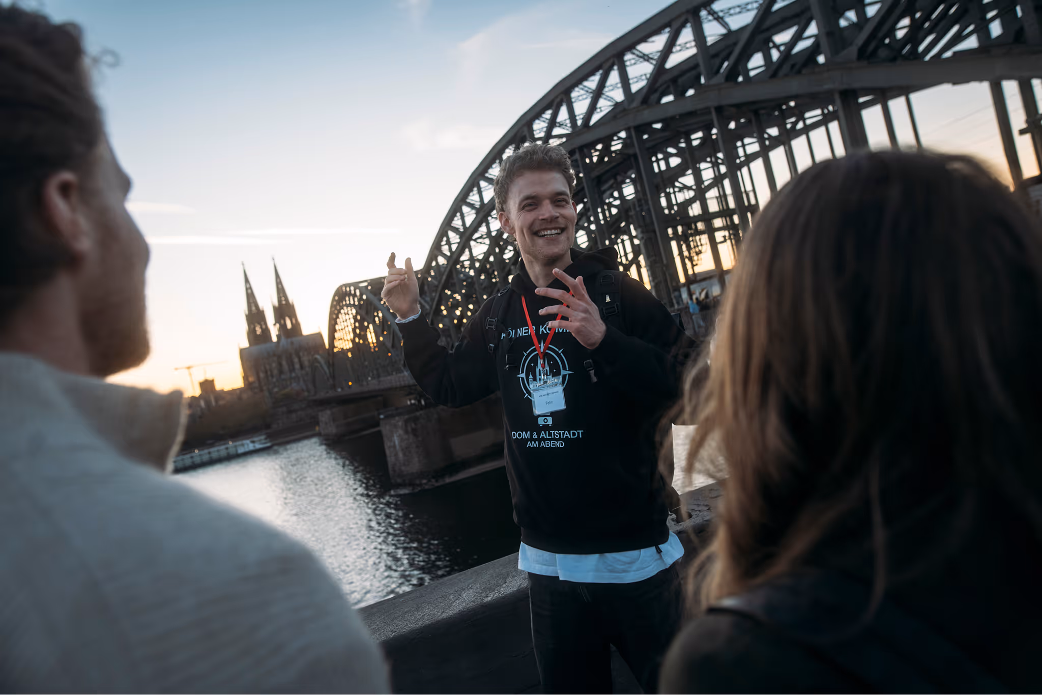 Kölner Kompass Tourguide erzählt Gästen etwas vor der Hohenzollernbrücke in Köln