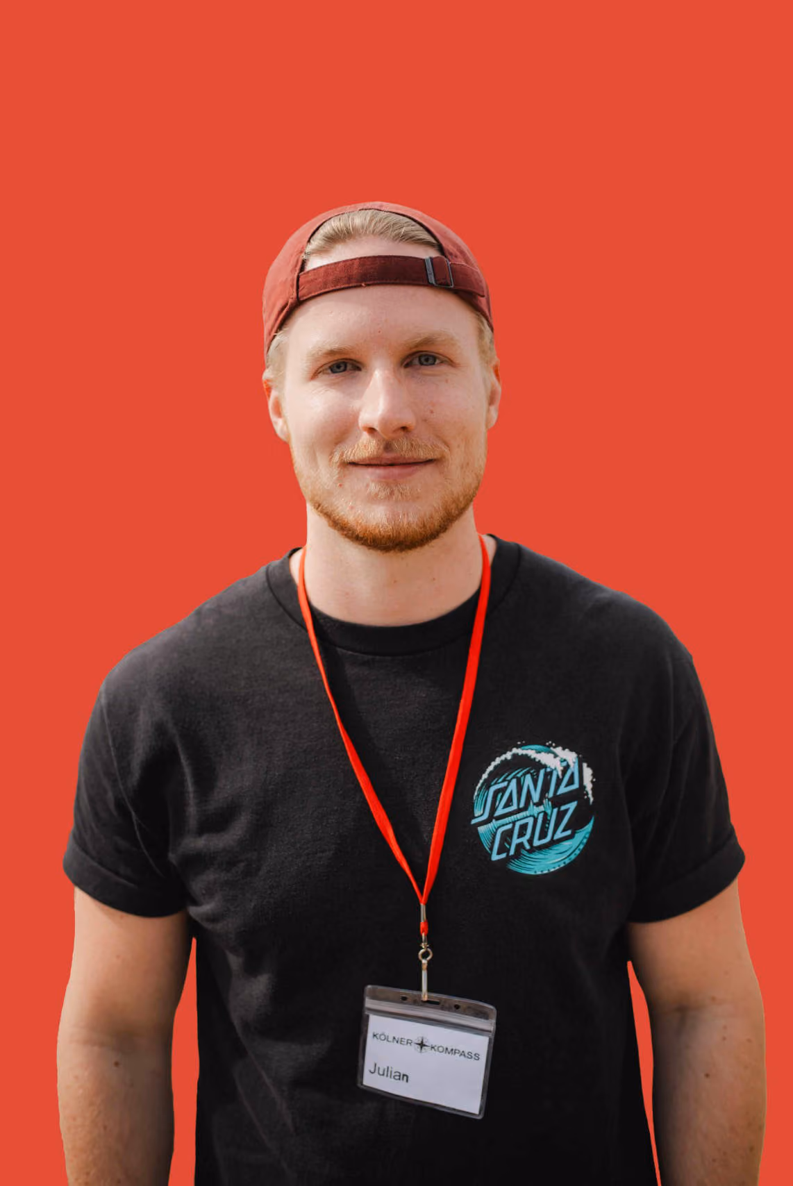 Kölner Kompass Tourguide mit Cap und Lanyard vor roter Wand