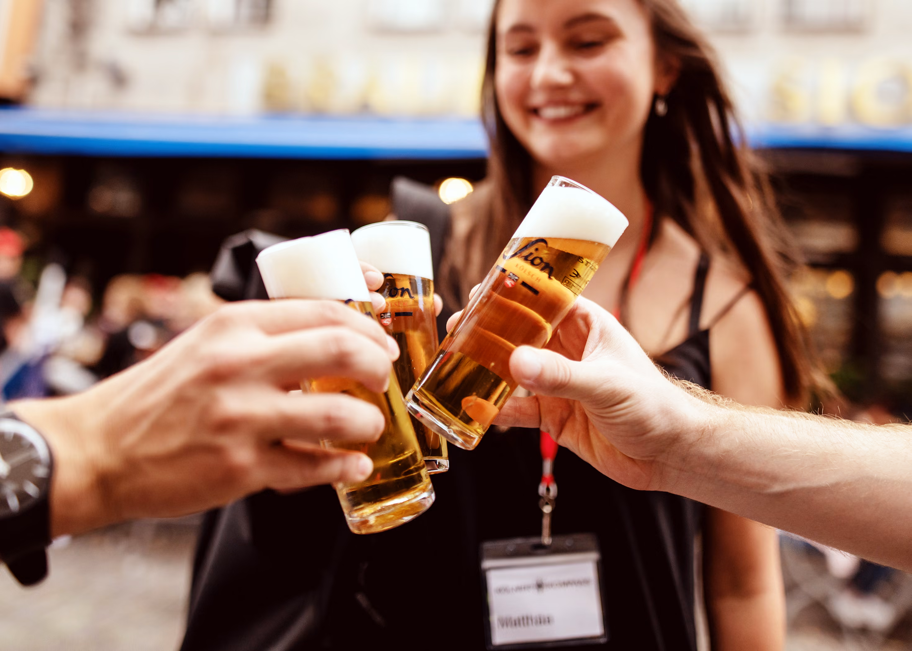Gäste der Brauhaustour stoßen draußen auf der Straße in Köln mit Kölsch an