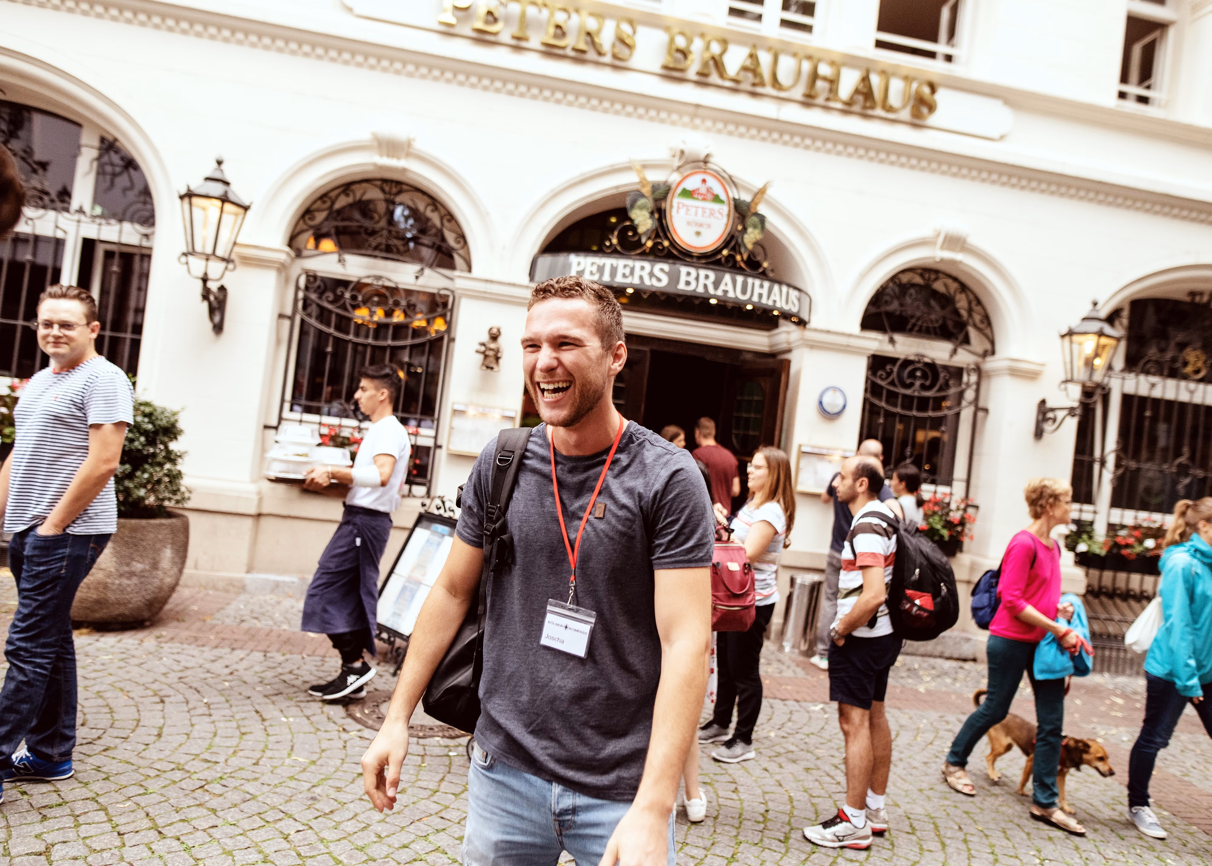 Tourguide mit Lanyard erzählt vor Peters Brauhaus in der Kölner Altstadt