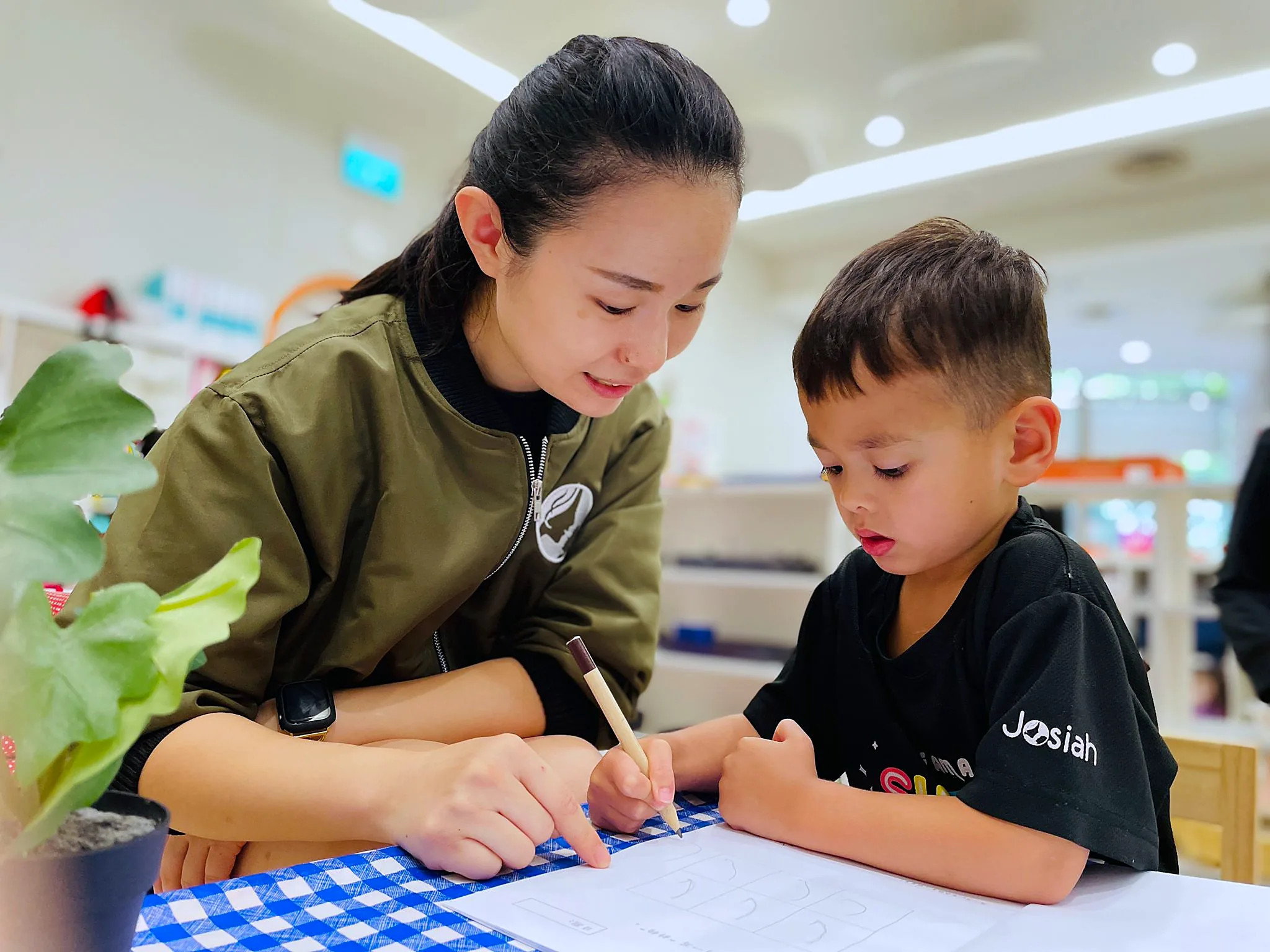 A Josiah teacher working one-to-one with a child at a low table.