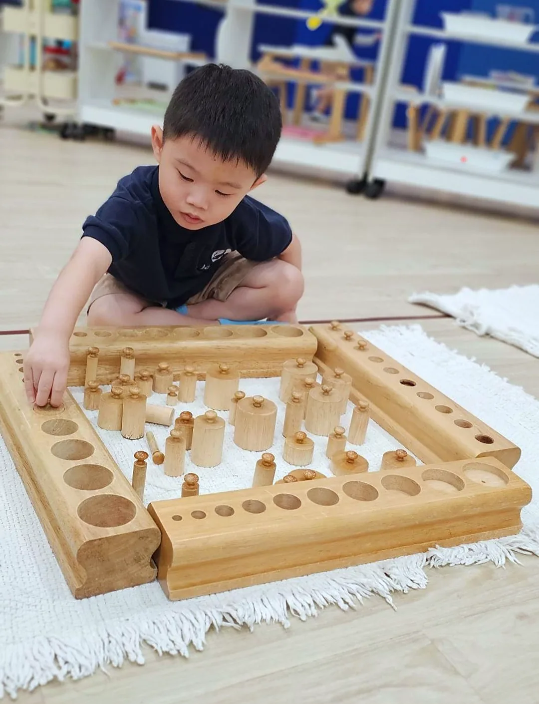 A Josiah child works on a Montessori exercise during the morning work cycle, eyes on the apparatus, hands steady.