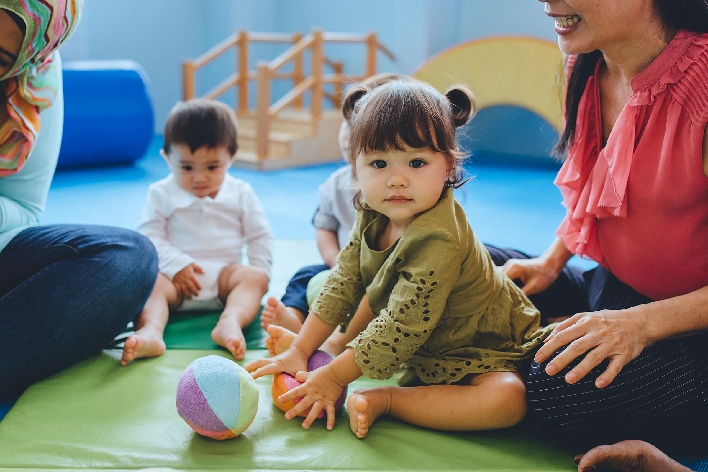 Toddler exploring a soft ball with a teacher in a Josiah infant and toddler class