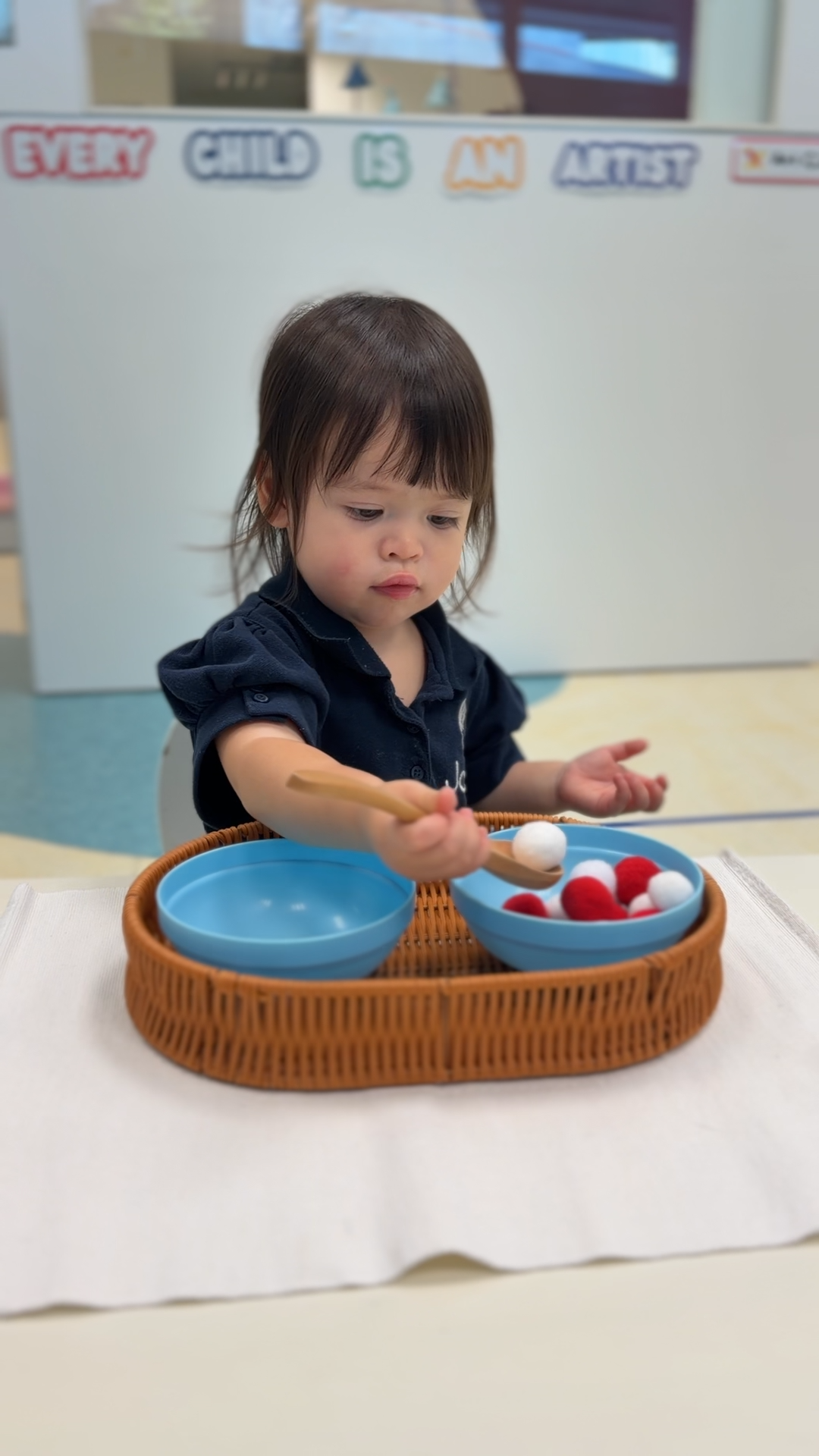 A toddler practising practical-life skills in Toddler Montessori