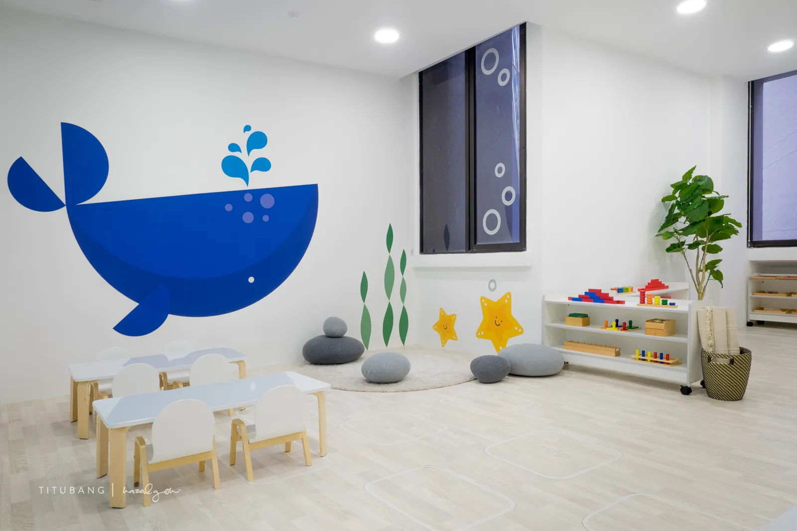 A classroom at Raffles Place with the whale wall and low work tables.