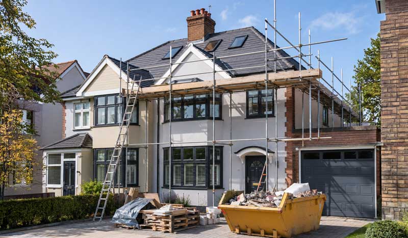 Property renovation in progress with scaffolding, roof replacement, exterior rendering, new windows, and home improvement work on a detached UK residential property.