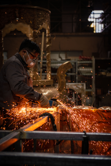 Metal chasing and surface refinement on a large bronze sculpture at Xinjiuding.