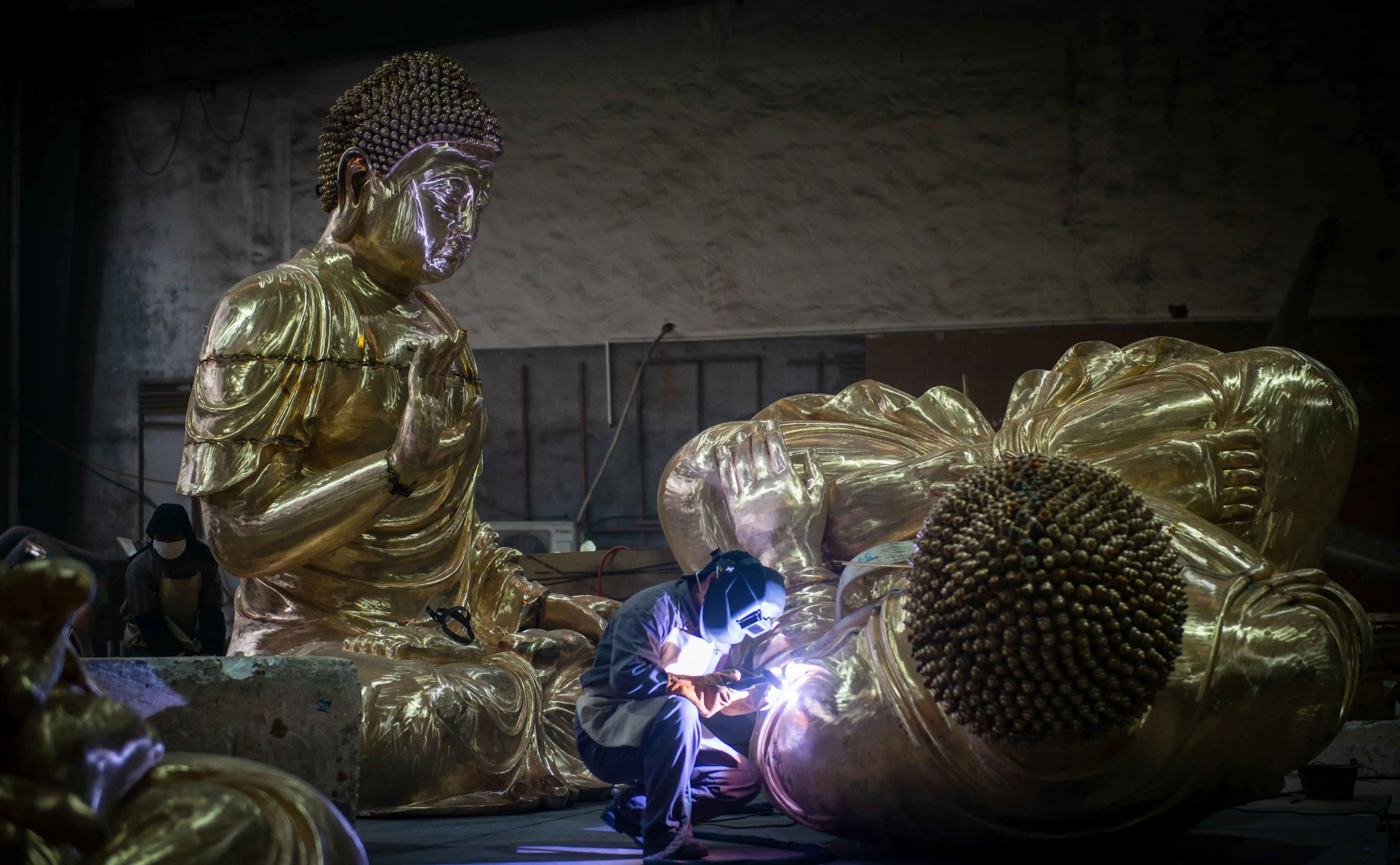 Large metal sculpture sections being aligned and assembled in the workshop.