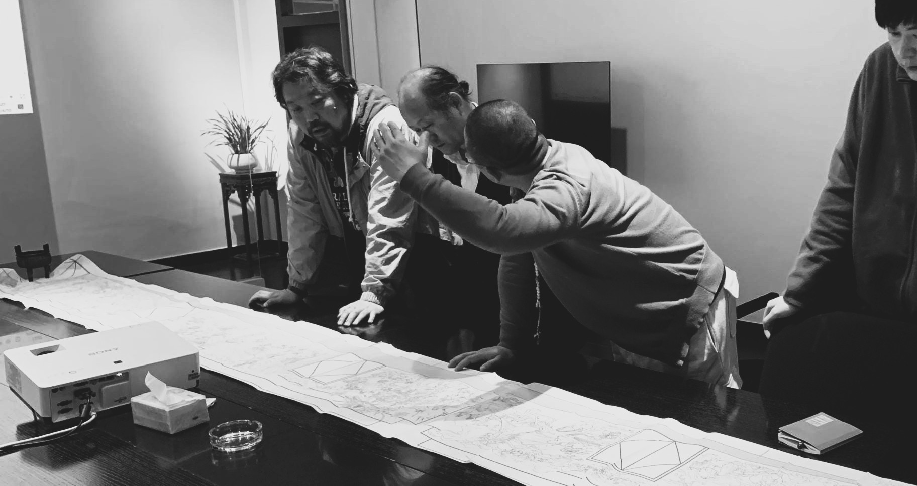 Project team discussing a large-format design drawing.