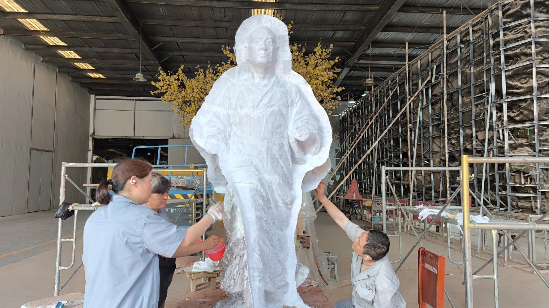 Craftspeople applying silicone layers to a standing figure model