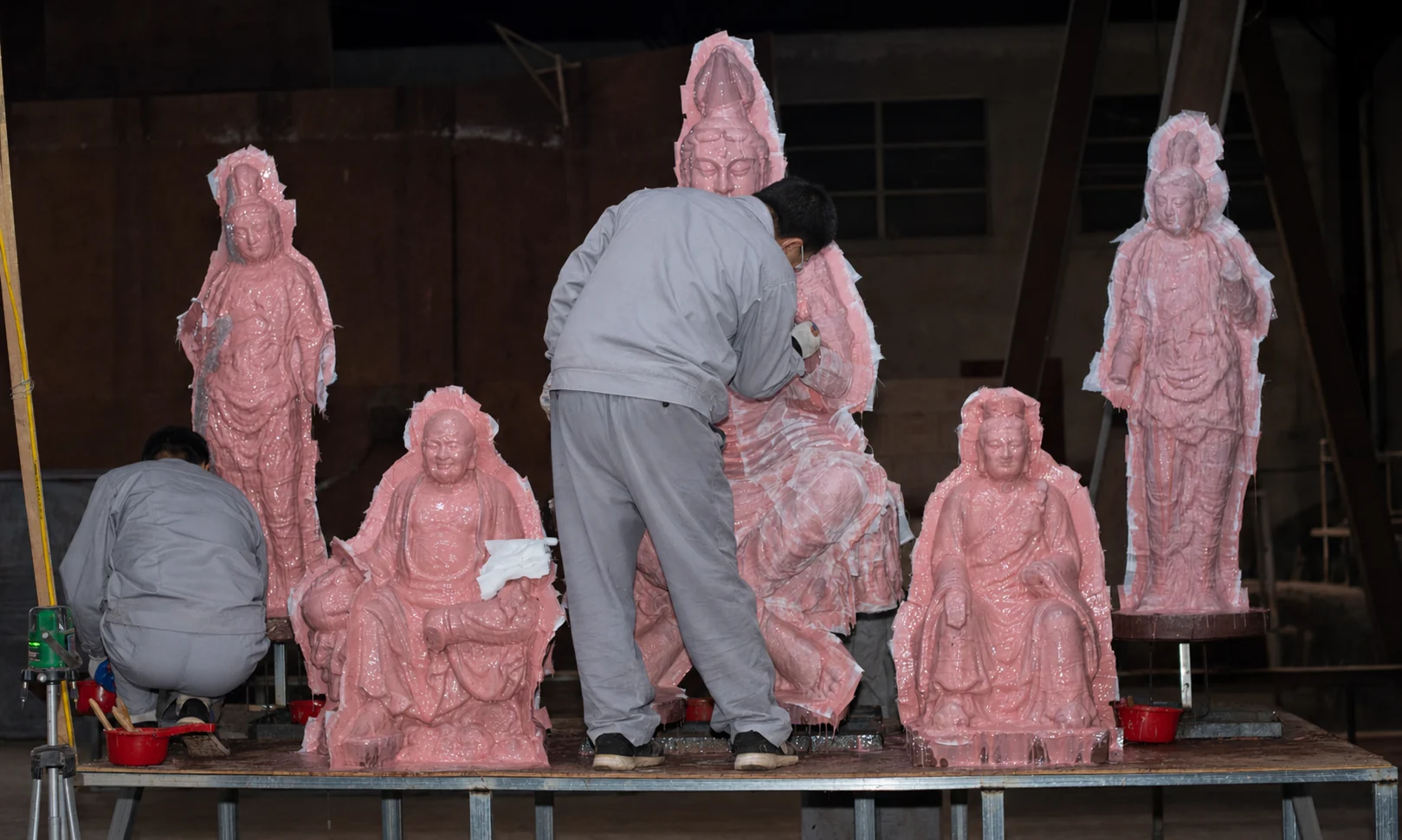 Craftspeople working on silicone moulds for several figure models