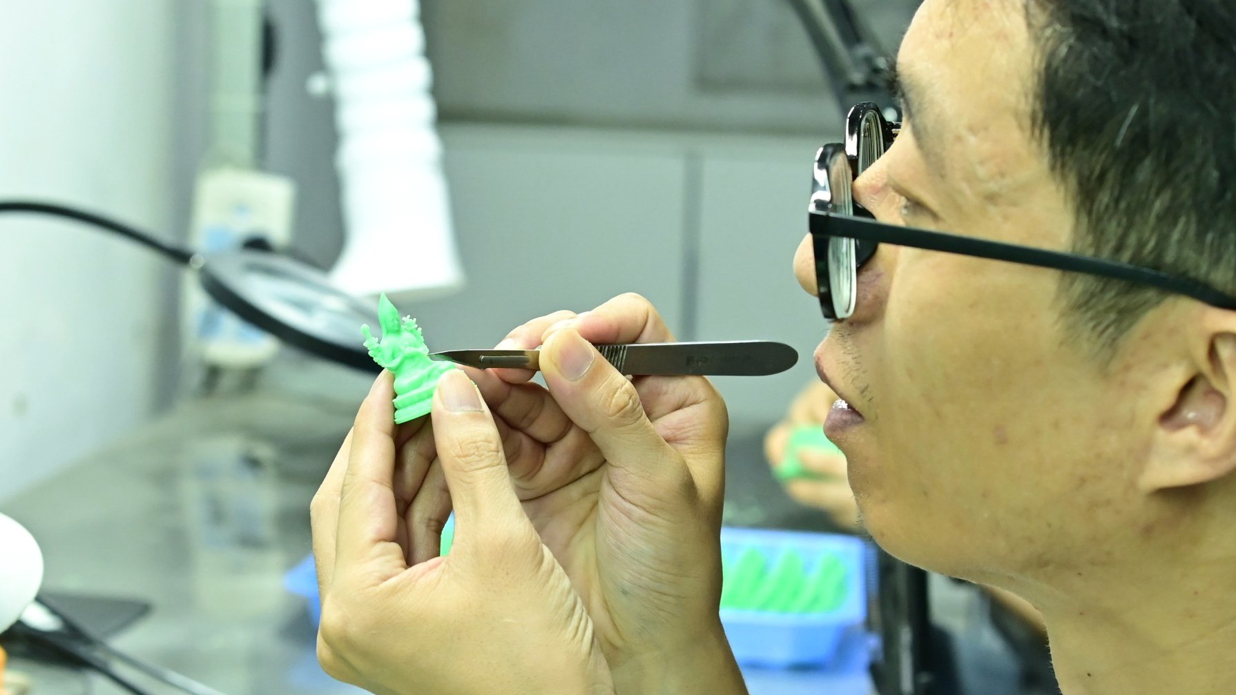 Artisan refines a small wax model for plaster investment casting.