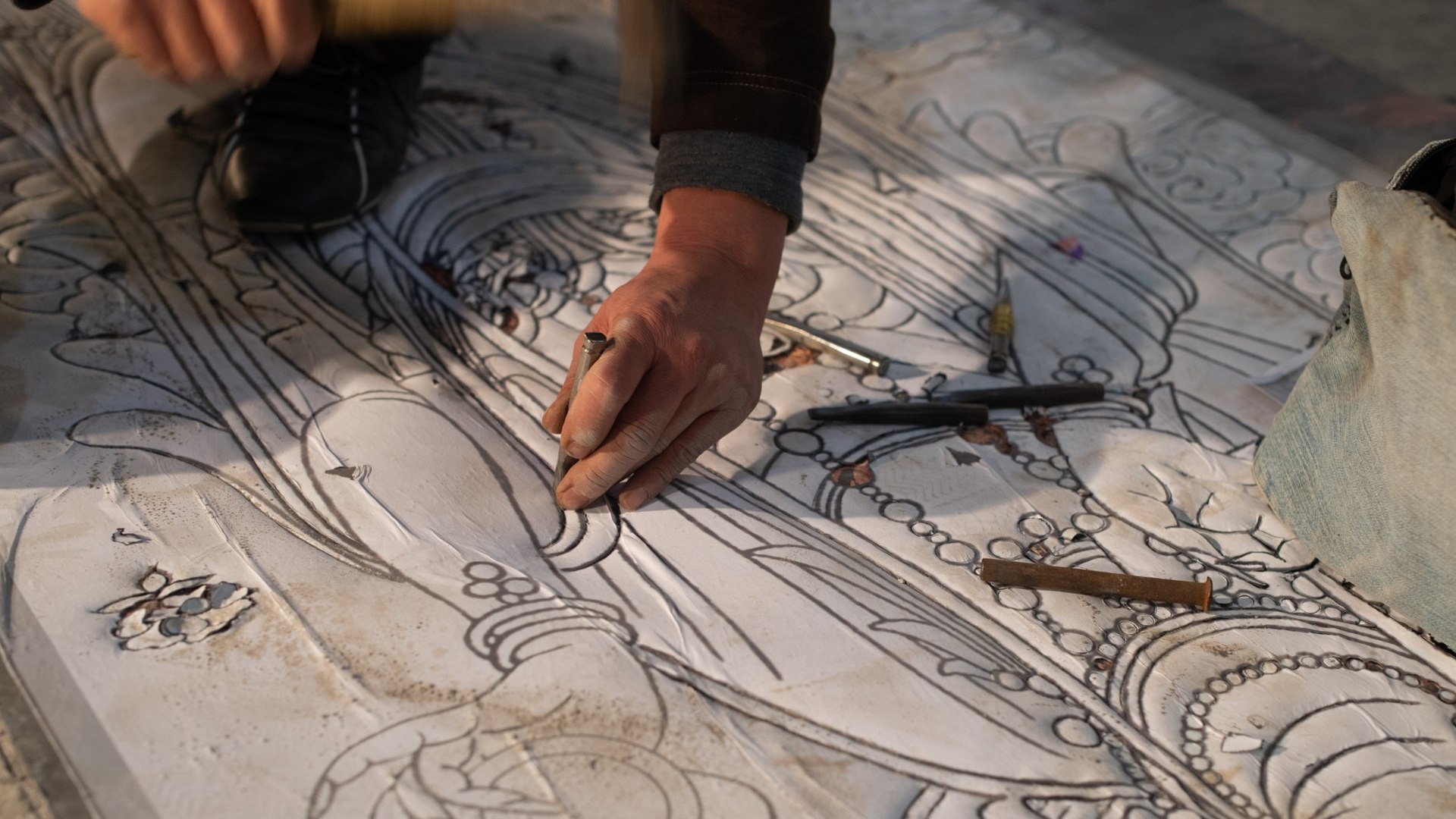 Artisan traces a detailed design in preparation for hand chasing.