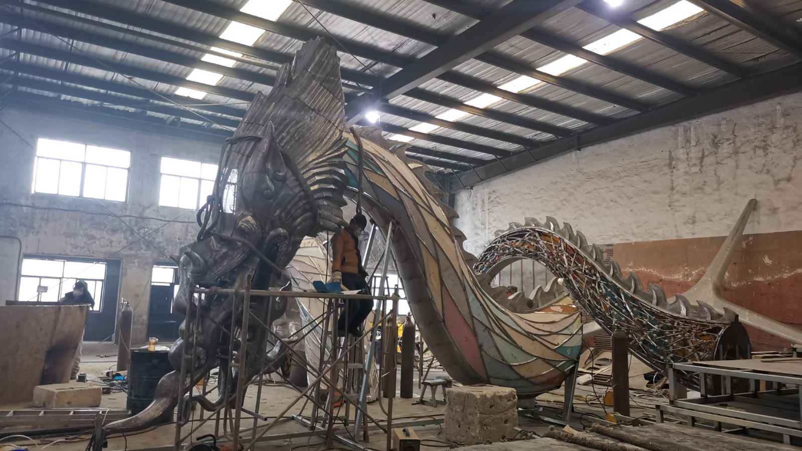 Dragon-shaped artwork with exposed framework during workshop assembly.