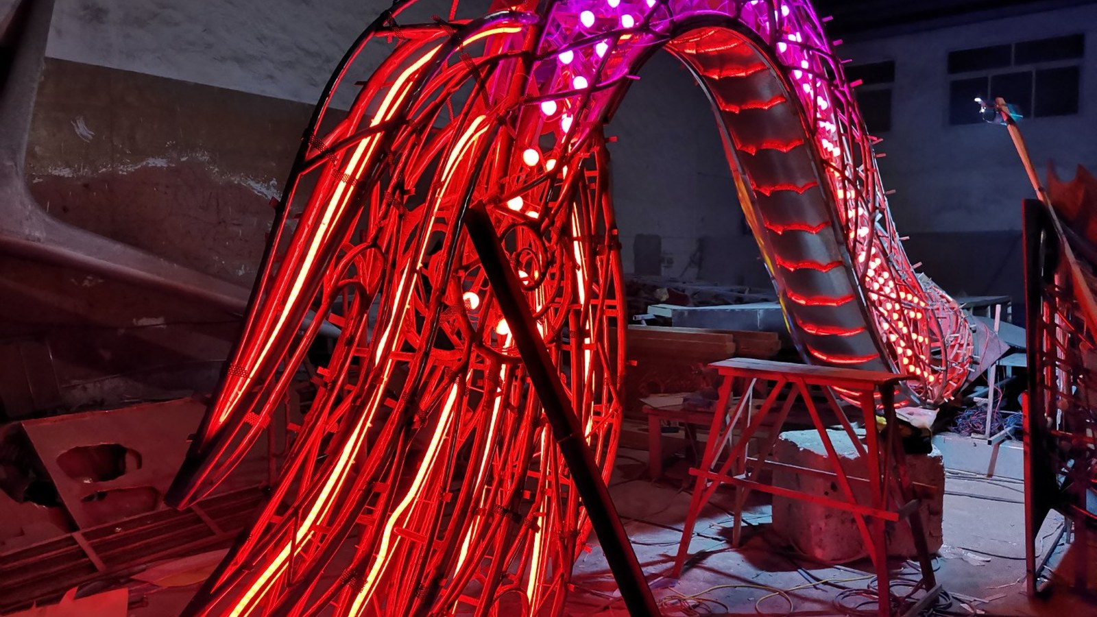 Red and purple lighting on an exposed dragon-shaped frame in the workshop.