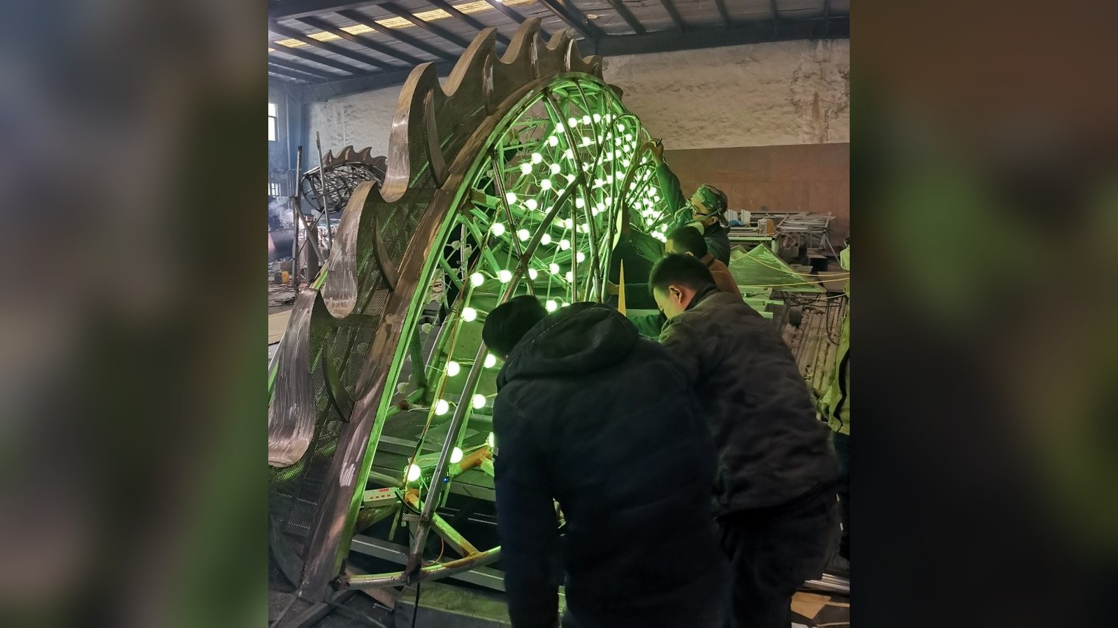 Workshop staff working on a sculptural frame fitted with green lights.