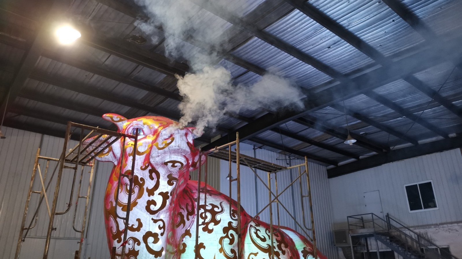Illuminated animal-shaped sculpture with a visible cloud of mist in the workshop.